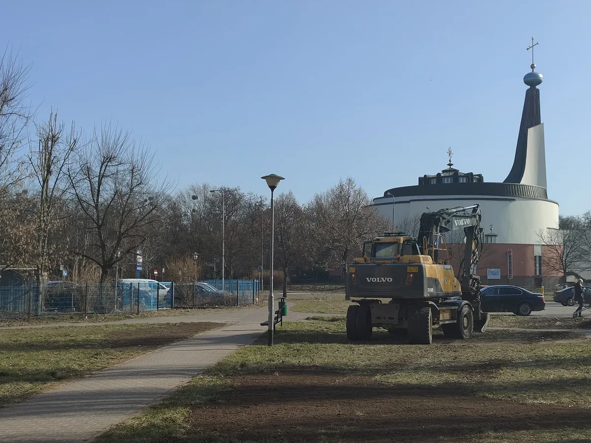 Niwelacja terenu zielonego Koparka wyrównująca teren zieleni miejskiej w pobliżu ścieżki spacerowej