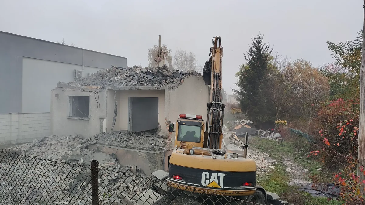 Dokończenie rozbiórki Ostatni fragment ściany budynku rozbierany koparką CAT