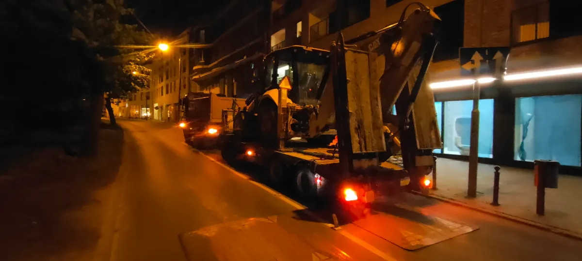Nocny transport maszyny Nocny załadunek koparki na lawetę przy oświetlonej ulicy